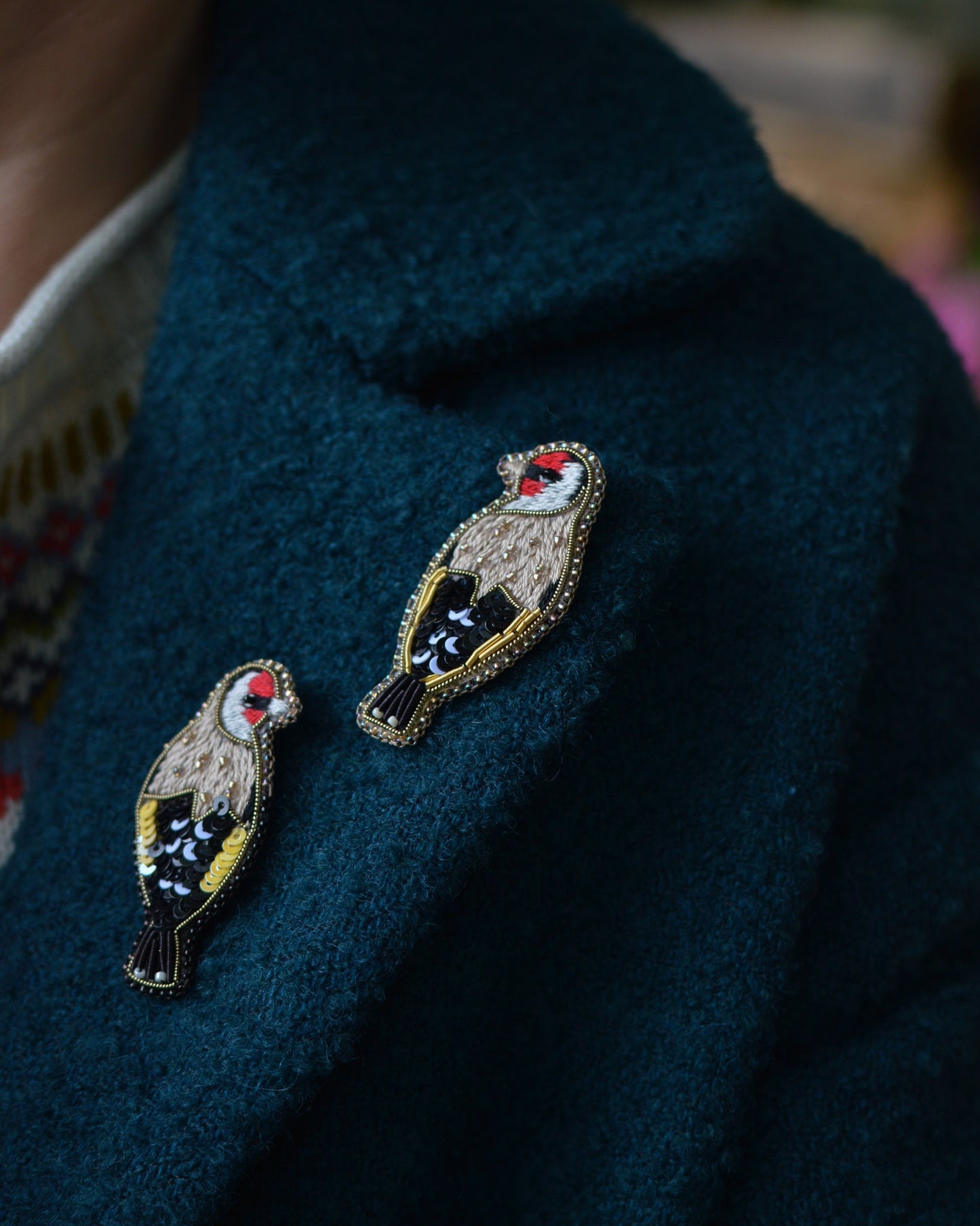 Embroidered goldfinch brooches worn on a cot lapel
