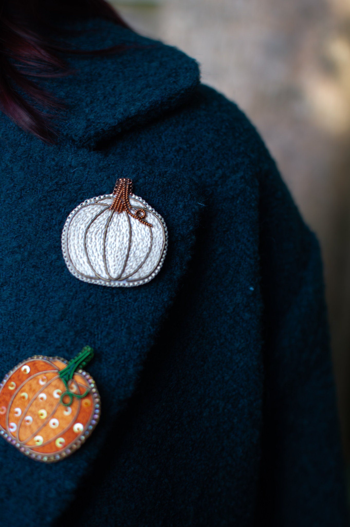 White and orange pumpkin embroidered brooches on a coat lapel