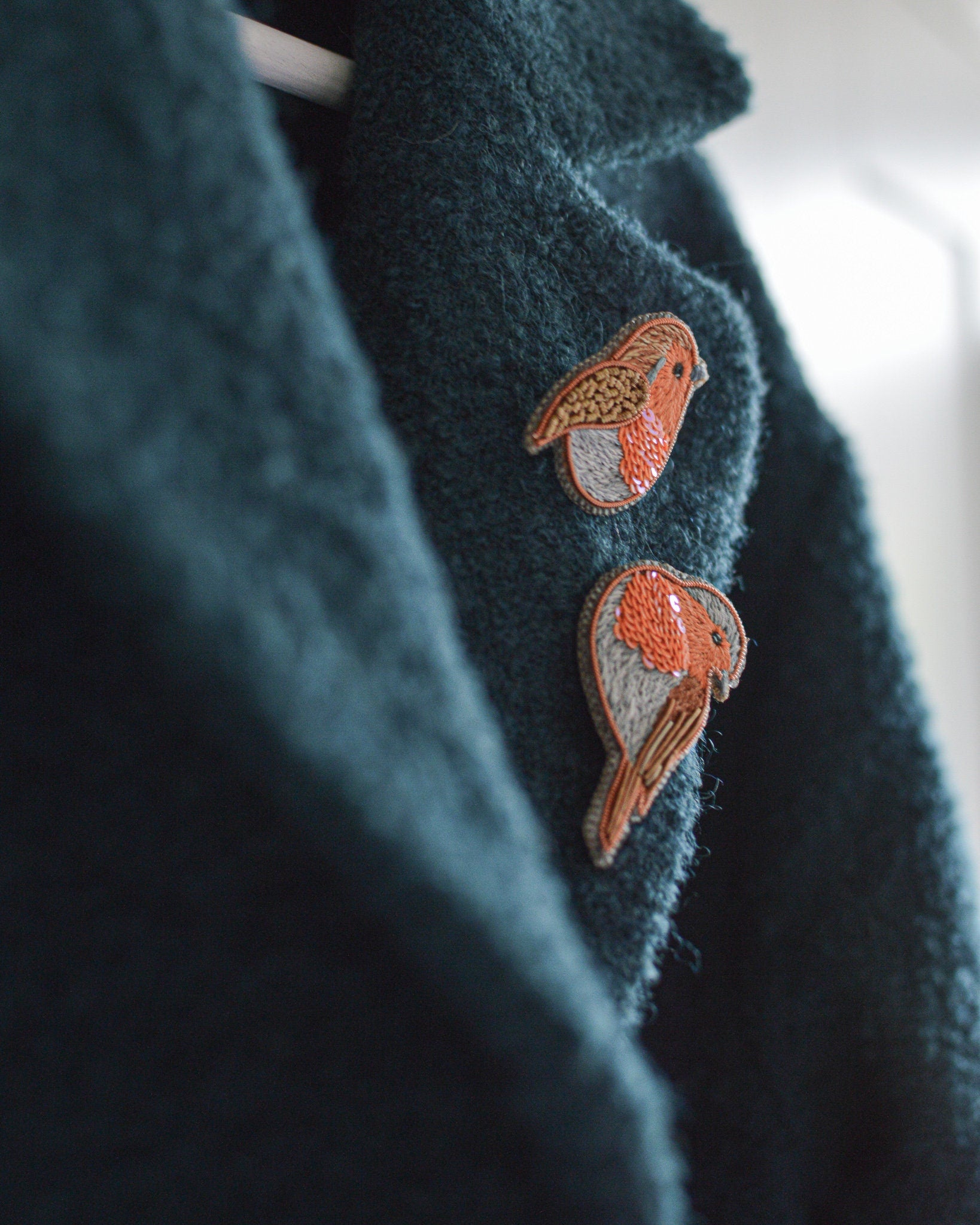 Embroidered robin brooches on a coat